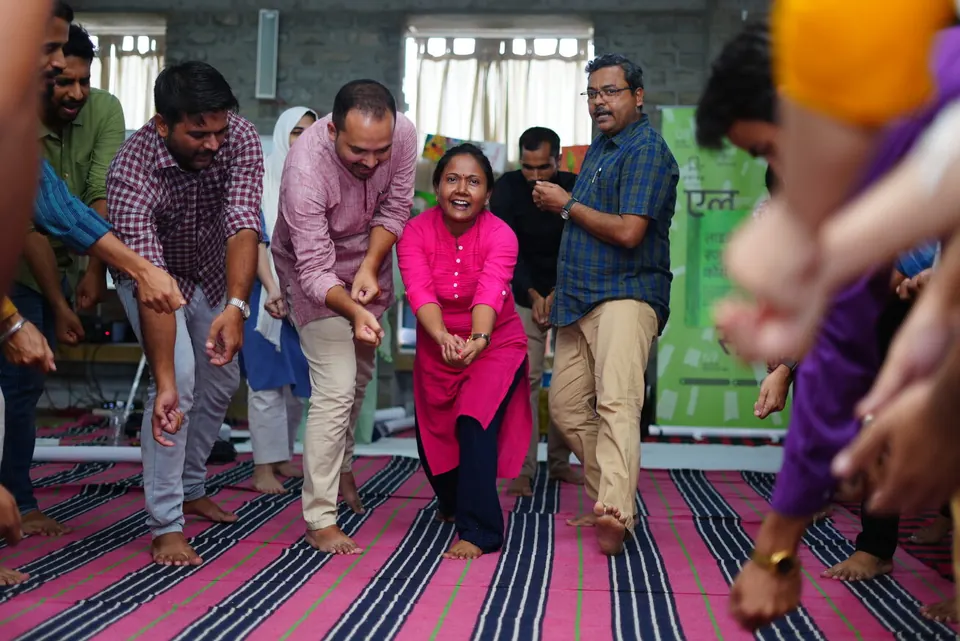 Anil and workshop participants joining in a lively group movement activity